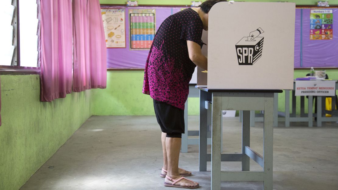 A voter wearing shorts and flip-flops fills out a ballot at a polling station in the Desa Petaling area of Kuala Lumpur, Malaysia, on Wednesday. Some voters were turned away by officials citing dress restrictions -- despite assurances that would not happen.