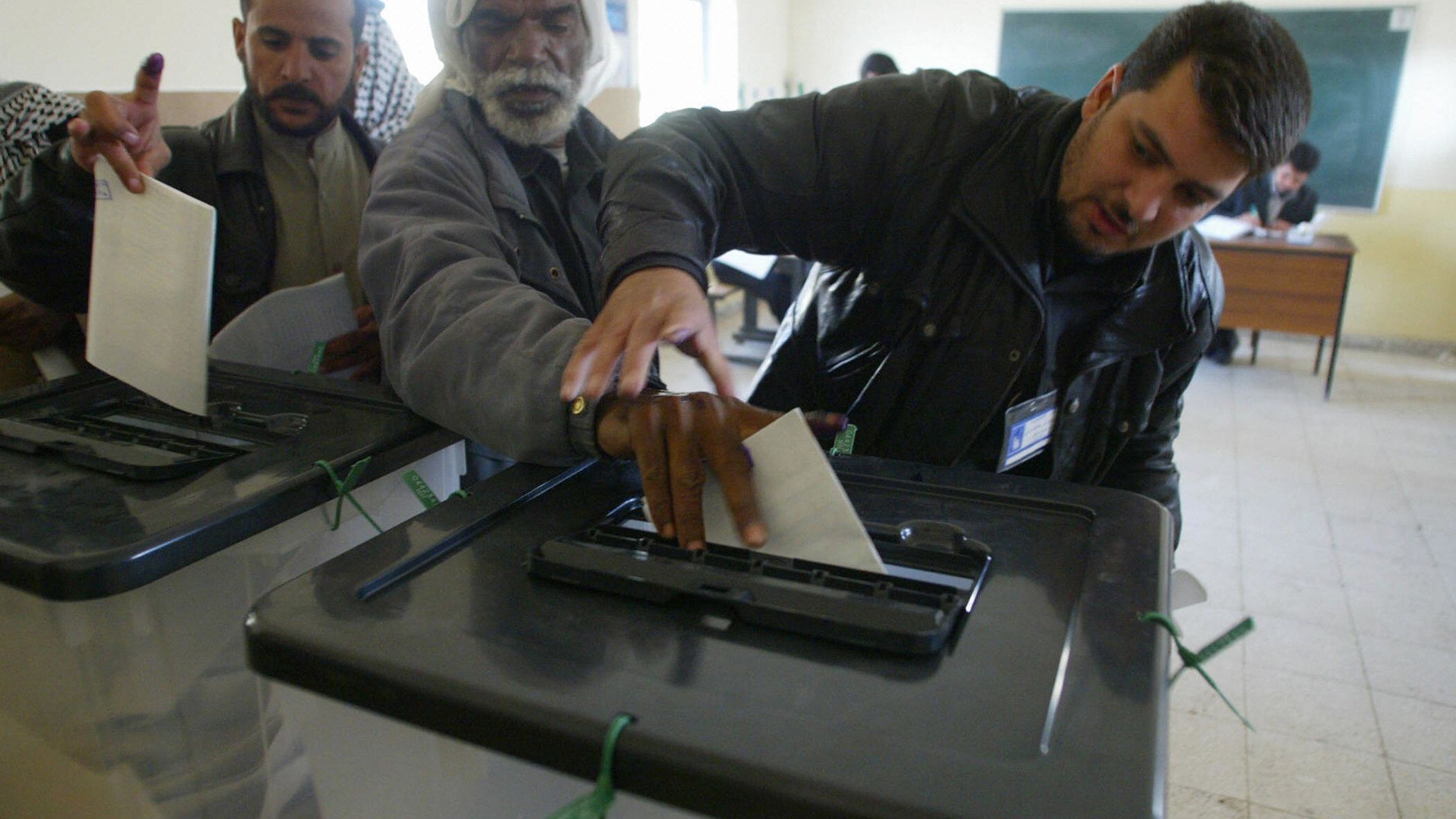 An official guides the hand of blind man Jawwad Shkeir, 56, as he cast his vote on 30 January 2005, in the southern holy city of Najaf. The elections were Iraq's first full vote since Saddam Hussein was routed from power in 2003.