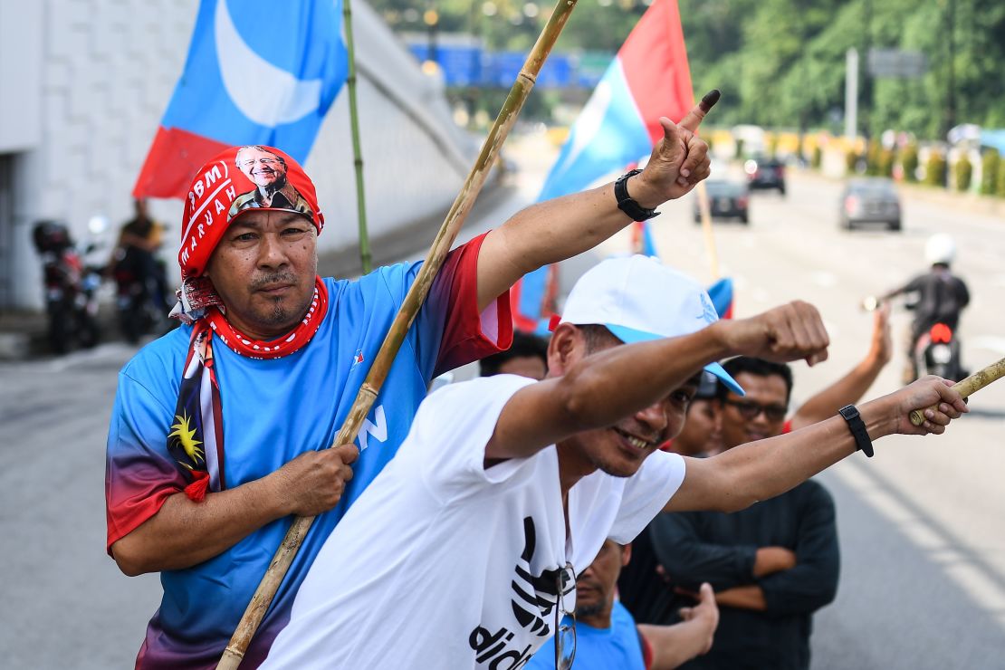 Supporters of Former Malaysian prime minister Mahathir Mohamad celebrate outside the National Palace.