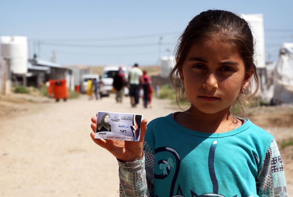 A displaced Iraqi girl holds an election campaign card, at the Hasan Sham camp in northern Iraq, in May 2018.