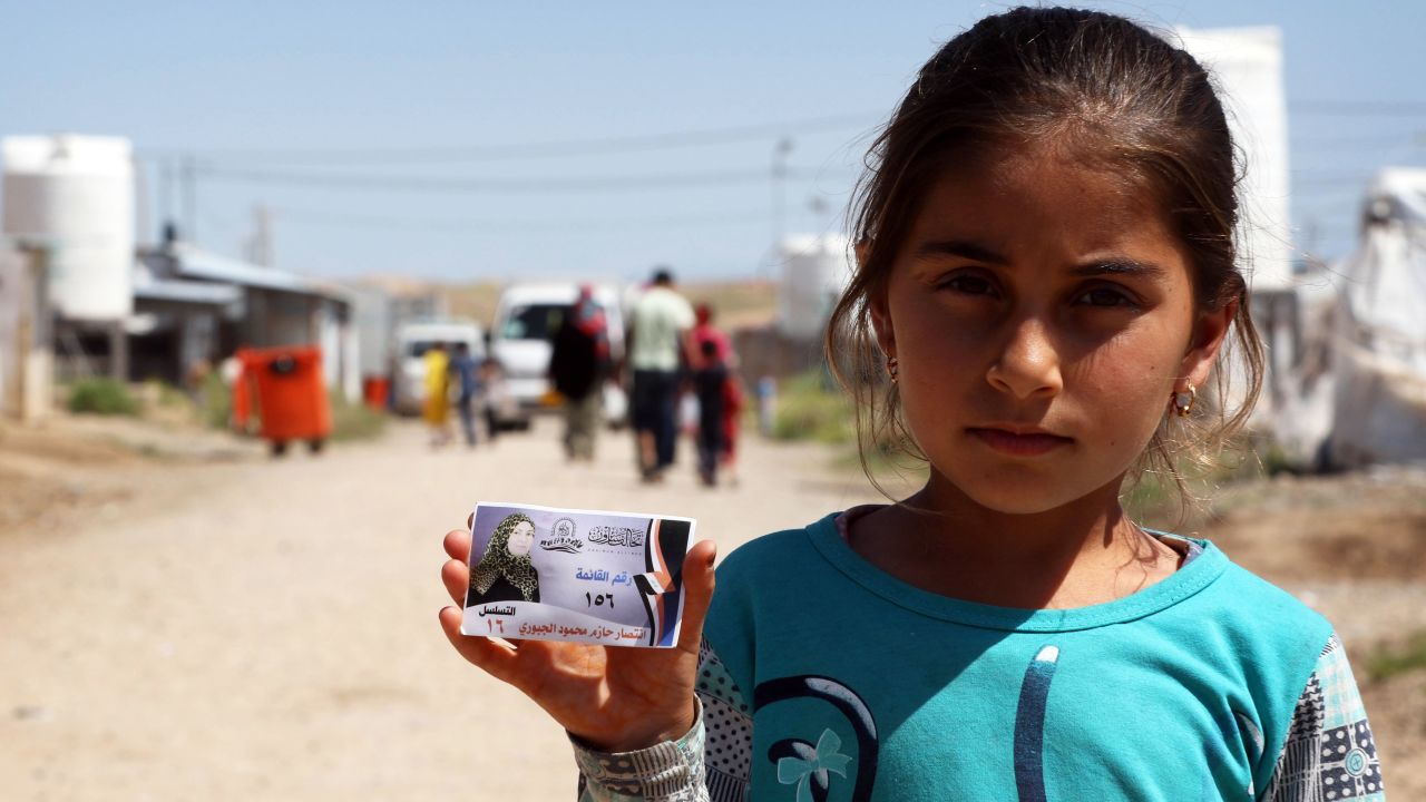 A displaced Iraqi girl holds an election campaign card, at the Hasan Sham camp in northern Iraq, in May 2018.