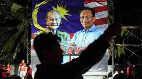 A supporter takes pictures in front of a banner showing Mahathir Mohamad, left, and jailed  opposition leader Anwar Ibrahim, right, during an April 15 election rally on Malaysia's island of Langkawi.