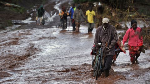 Villagers in Solai, Kenya, cross floodwaters on Thursday, May 10, a day after the Patel Dam burst following weeks of torrential rain. At least 45 people have died, officials said, after homes in the community were swept away. Dozens of people remain missing.