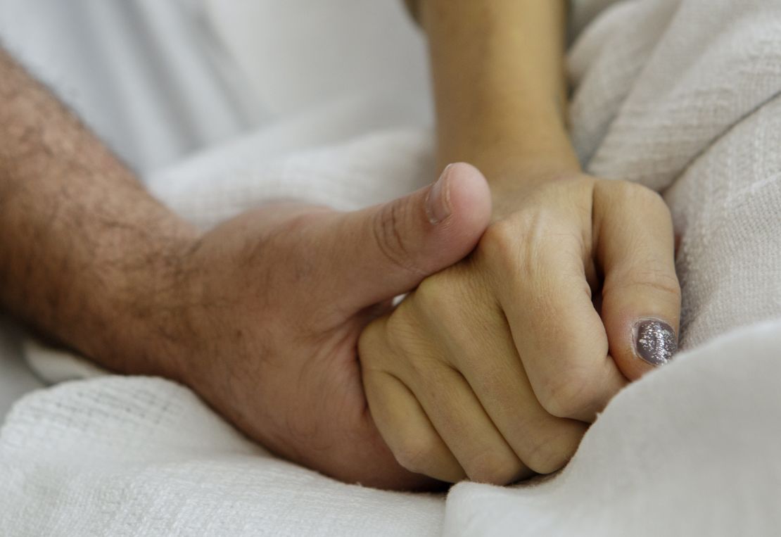 Erika Zak and her husband, Scott Powers, lock hands during a recent hospital visit. The two met 20 years ago. 