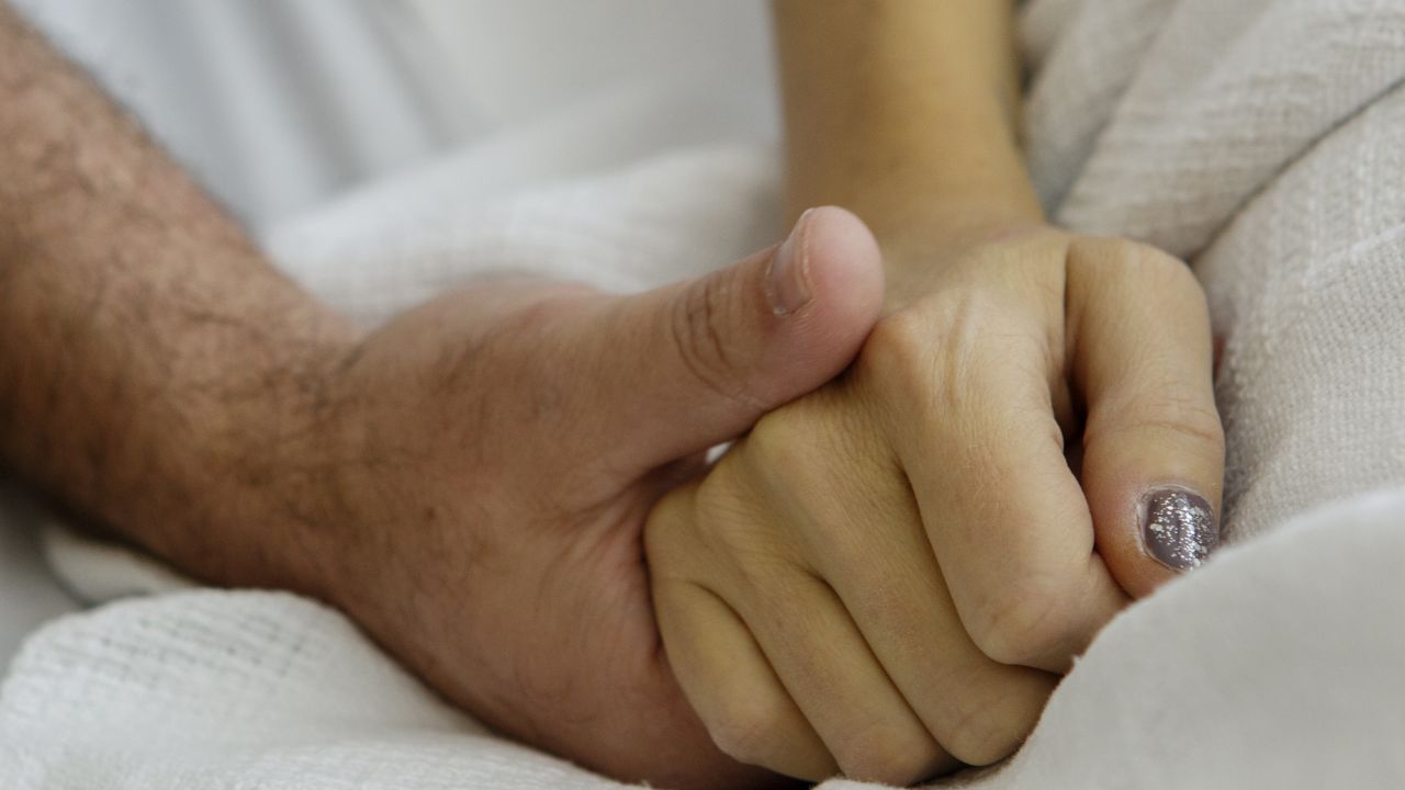 Erika Zak and her husband, Scott Powers, lock hands during a recent hospital visit. The two met 20 years ago.