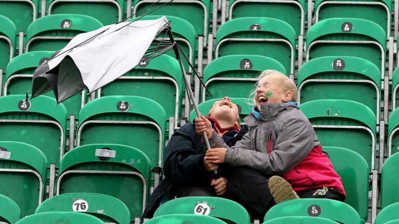 Twelve-year-old Aran Cavanagh, left, and his sister Joise, 11, battle with their umbrella as wind and rain sweep across Malahide Cricket Club in Dublin as the start of play is delayed on the first day of the test match between Ireland and Pakistan on Friday, May 11. 