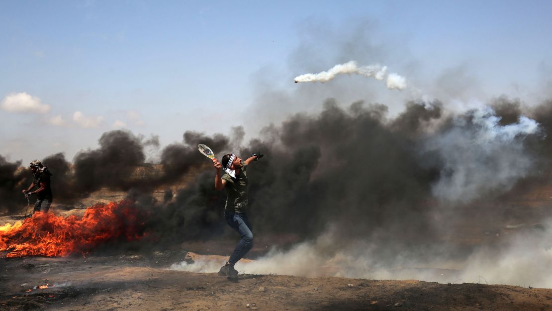 A demonstrator uses a racket to return a tear gas canister fired by Israeli troops during clashes at the Gaza border on Friday, May 11.