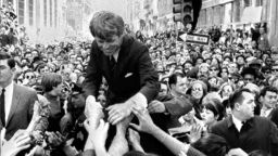 Senator Robert Kennedy is surrounded by hundreds of people as he leans down to shake hands during a campaign appearance at a street corner in central Philadelphia, April 2, 1968. (AP Photo/Warren M. Winterbottom)