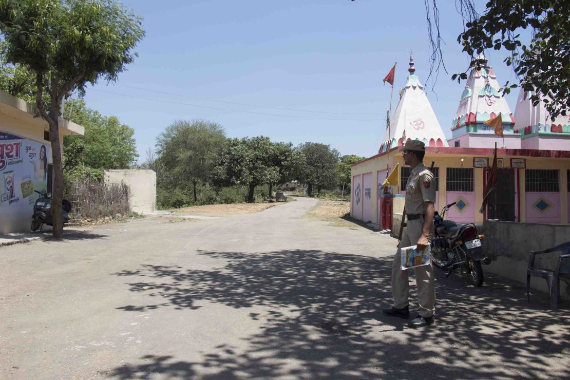 A police officer guards the main entrance to Rasana village. Local police have increased their presence in the village following the rape and murder of the Muslim girl.