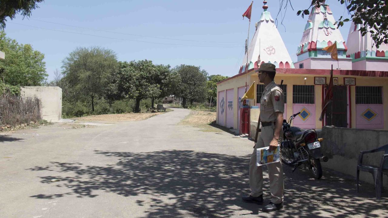 A police officer guards the main entrance to Rasana village. Local police have increased their presence in the village following the rape and murder of the Muslim girl.