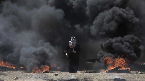 A Palestinian woman walks through black smoke from burning tires during a protest in Gaza on Monday. 