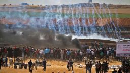 TOPSHOT - Palestinian protesters look at tear gas and smoke billowing from burning tyres, east of Gaza City on May 14, 2018, as Palestinians readied for protests over the inauguration of the US embassy following its controversial move to Jerusalem. (Photo by Mohammed ABED / AFP)        (Photo credit should read MOHAMMED ABED/AFP/Getty Images)