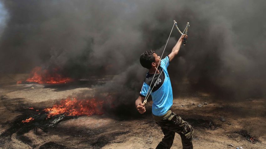 A Palestinian man uses a slingshot during clashes with Israeli forces along the border with the Gaza strip east of Khan Yunis on May 14, 2018, as Palestinians protest over the inauguration of the US embassy following its controversial move to Jerusalem. (Photo by SAID KHATIB / AFP)        (Photo credit should read SAID KHATIB/AFP/Getty Images)
