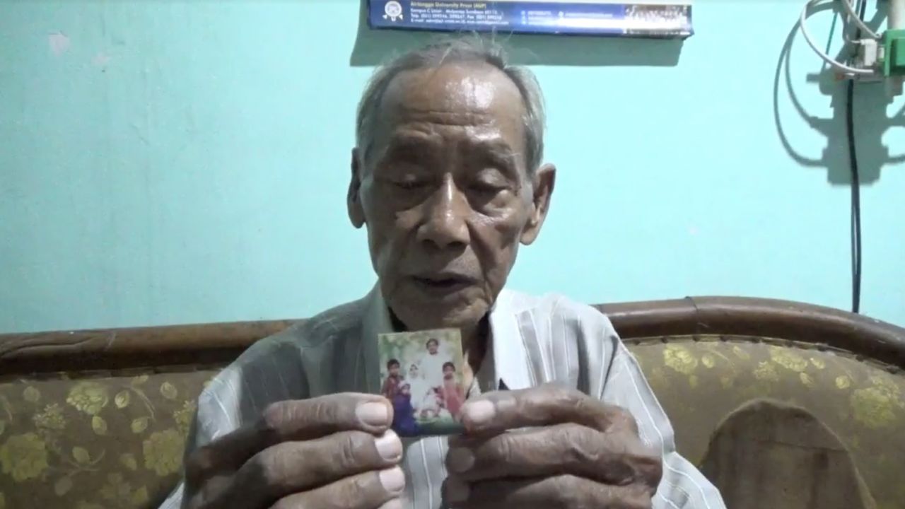 Raden Doddy Oesodo, Dita Oepriarto's father, holds a family photo.