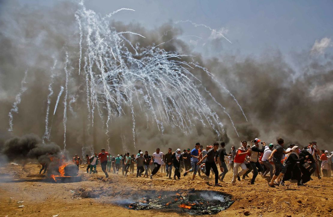 Palestinians run for cover from tear gas during clashes on Monday. 