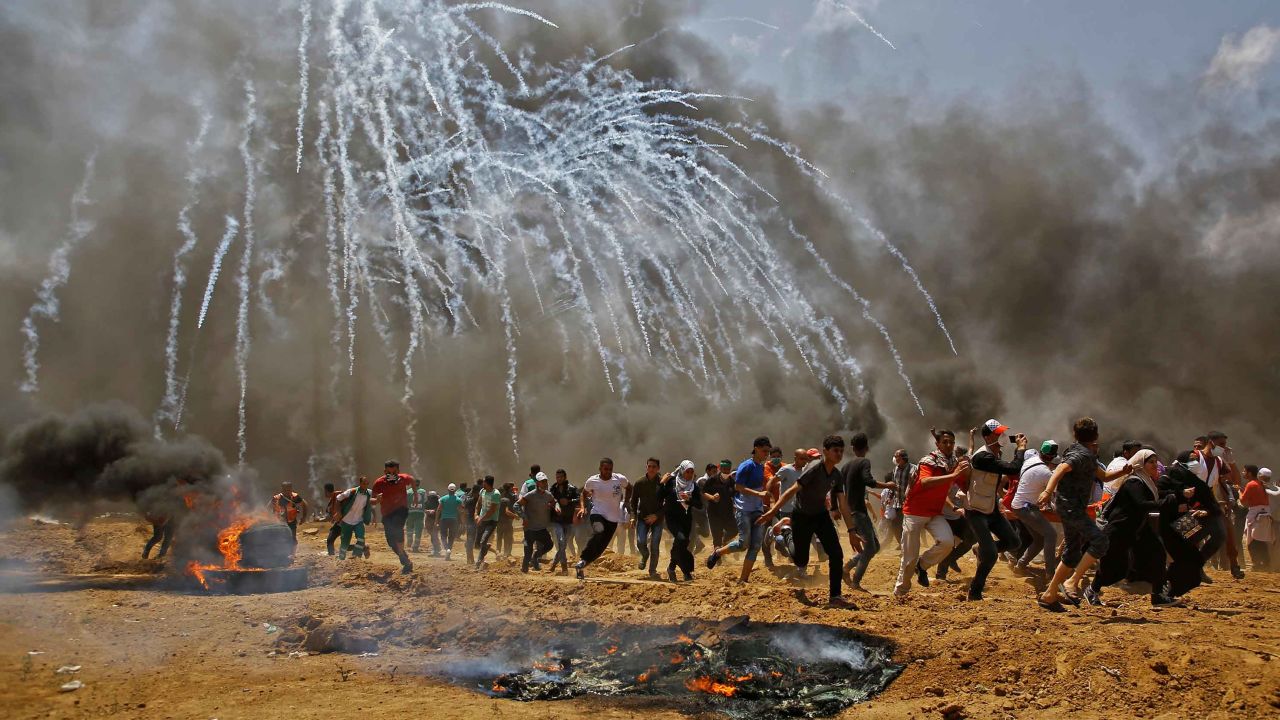 Palestinians run for cover from tear gas during clashes on Monday. 
