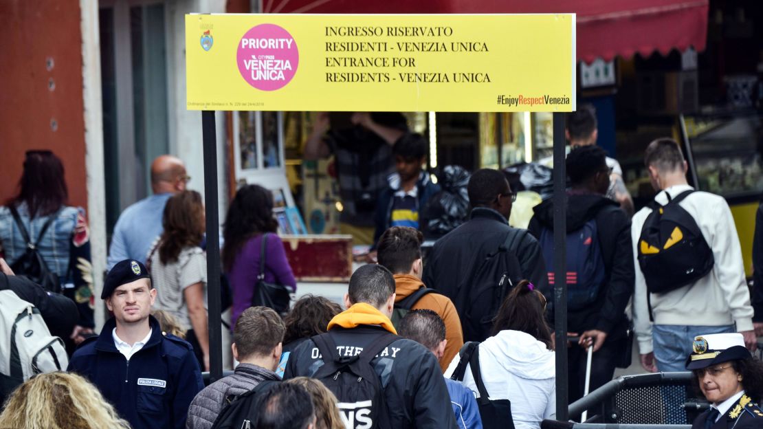 People pass through turnstiles designed to limit the flows of tourists in Venice.