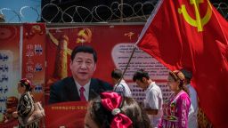 KASHGAR, CHINA - JUNE 30: Ethnic Uyghur members of the Communist Party of China carry a flag past a billboard of Chinese President Xi Jinping as they take part in an organized tour on June 30, 2017 in the old town of Kashgar, in the far western Xinjiang province, China. Kashgar has long been considered the cultural heart of Xinjiang for the province's nearly 10 million Muslim Uyghurs. At an historic crossroads linking China  to Asia, the Middle East, and Europe, the city has  changed under Chinese rule with government development, unofficial Han Chinese settlement to the western province, and restrictions imposed by the Communist Party. Beijing says it regards Kashgar's development as an improvement to the local economy, but many Uyghurs consider it a threat that is eroding their language, traditions, and cultural identity.  The friction has fuelled a separatist movement that has sometimes turned violent, triggering a crackdown on what China's government considers 'terrorist acts' by religious extremists.  Tension has increased with stepped up security in the city and the enforcement of measures including restrictions at mosques. (Photo by Kevin Frayer/Getty Images)