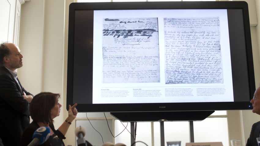 A video shows the text underneath two taped off pages from Anne Frank's diary during a press conference at The Anne Frank Foundation's office in Amsterdam, Netherlands, Tuesday, May 15, 2018. Left standing is the foundation's director Ronald Leopold. Researchers have used digital photo editing techniques to uncover the text on two pages from Anne Frank's world famous diary that the teenage Jewish diarist had covered with brown masking paper, revealing risque jokes and an explanation of sex and prostitution. (AP Photo/Peter Dejong)