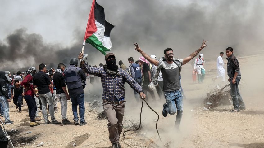 TOPSHOT - Palestinian protesters pull a metal cable as they try to take down a section of barbed wire during clashes with Israeli forces on April 20, 2018, east of Khan Yunis, in the southern Gaza Strip during mass protests along the border of the Palestinian enclave, dubbed 