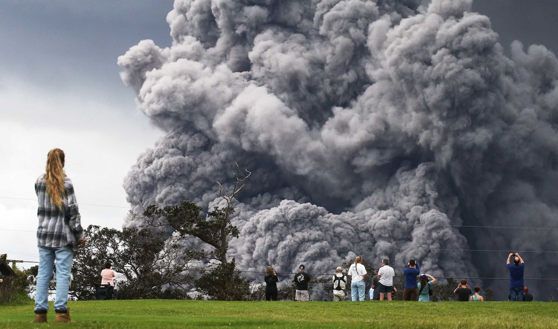 People watch at a golf course as an ash plume rises from the Kilauea volcano on the Big Island. 