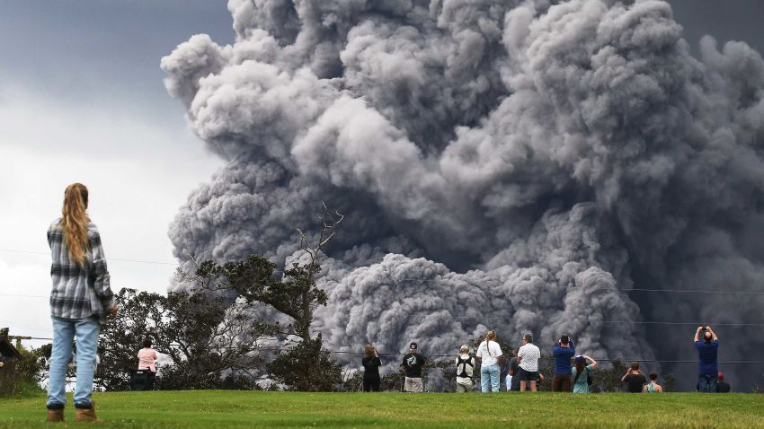 HAWAII VOLCANOES NATIONAL PARK, HI - MAY 15:  People watch at a golf course as an ash plume rises in the distance from the Kilauea volcano on Hawaii's Big Island on May 15, 2018 in Hawaii Volcanoes National Park, Hawaii. The U.S. Geological Survey said a recent lowering of the lava lake at the volcano's Halemaumau crater 'has raised the potential for explosive eruptions' at the volcano.  (Photo by Mario Tama/Getty Images)