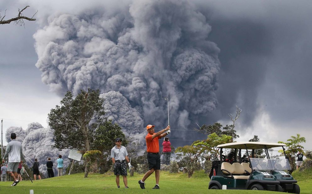 Stunning photos taken at Hawaii's Big Island on Tuesday show golfers coolly hitting the links even as a monstrous ash plume looms behind them from the Kilaueau volcano on May 15, 2018 at Hawaii Volcanoes National Park.