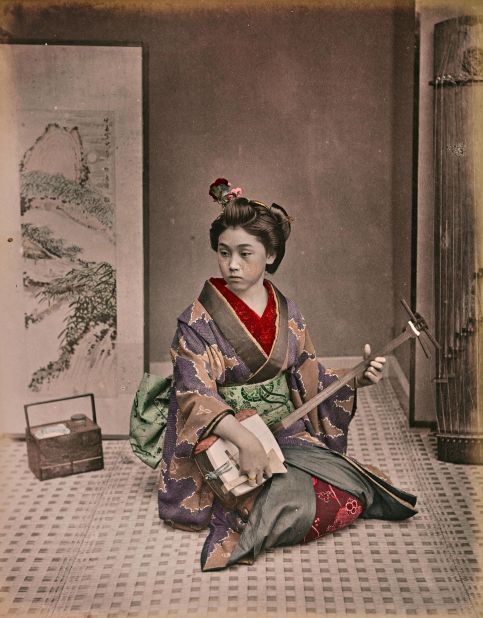 A young geisha plays a traditional instrument.