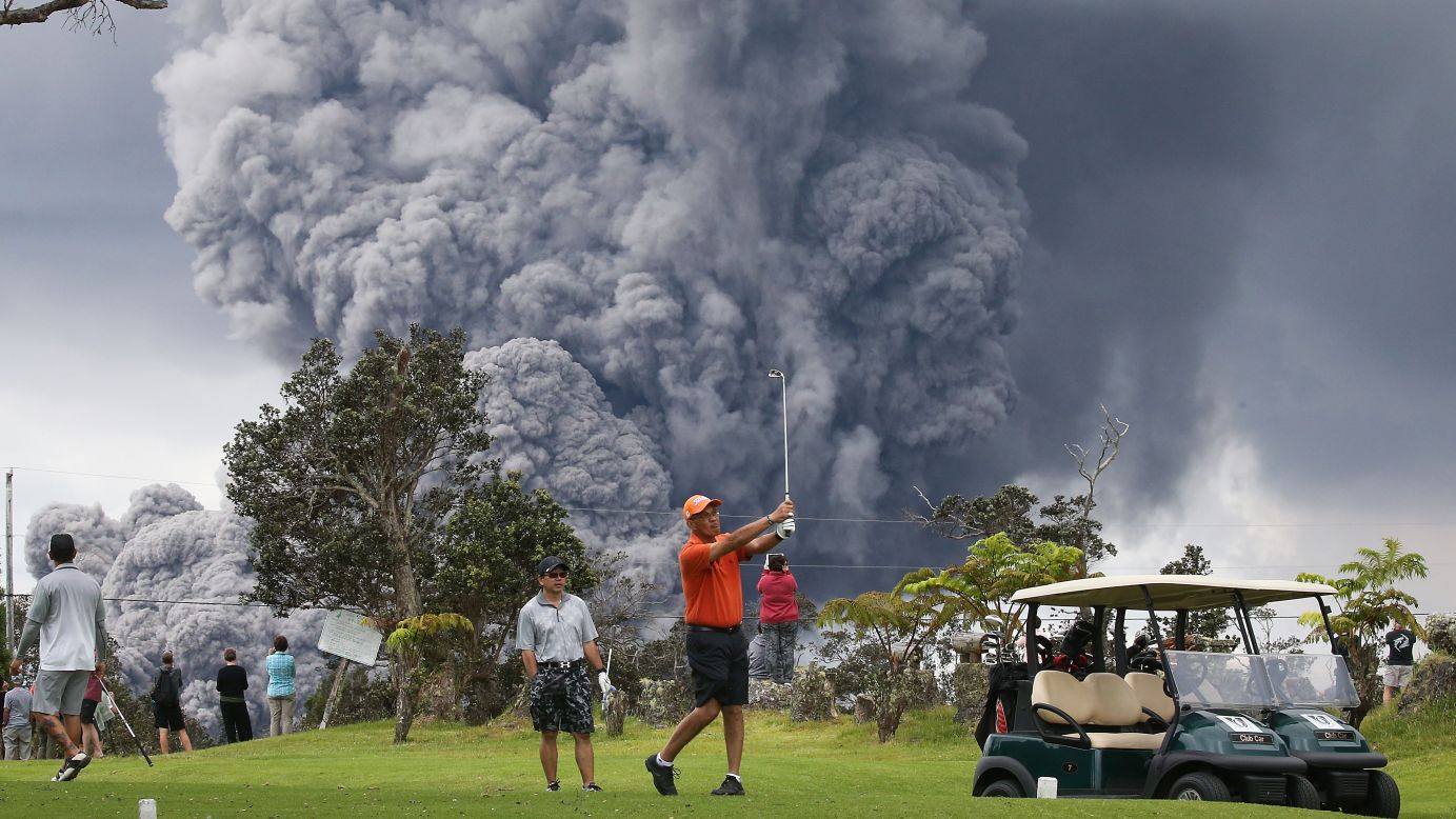 People play golf on Hawaii's Big Island as an ash plume from the Kilauea volcano rises in the distance on Tuesday, May 15.  The volcano erupted earlier this month, sending a smoldering flow of lava into residential areas. <a href="https://www.cnn.com/interactive/2018/05/us/hawaii-kilauea-volcano-eruption-cnnphotos/" target="_blank">See more photos</a>