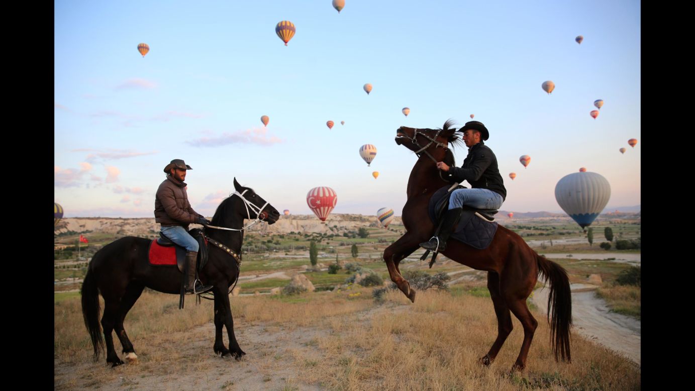 Men ride horses as hot-air balloons fly in Turkey's Cappadocia region on Monday, May 14. Cappadocia is known as "The Land of Beautiful Horses," and it is also famous for its "fairy chimney" rocks, hot-air balloon trips and underground cities.