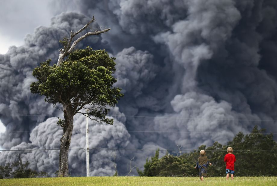 Boys watch at a golf course as an ash plume rises in the distance from the Kilauea volcano on Hawaii's Big Island on Tuesday.