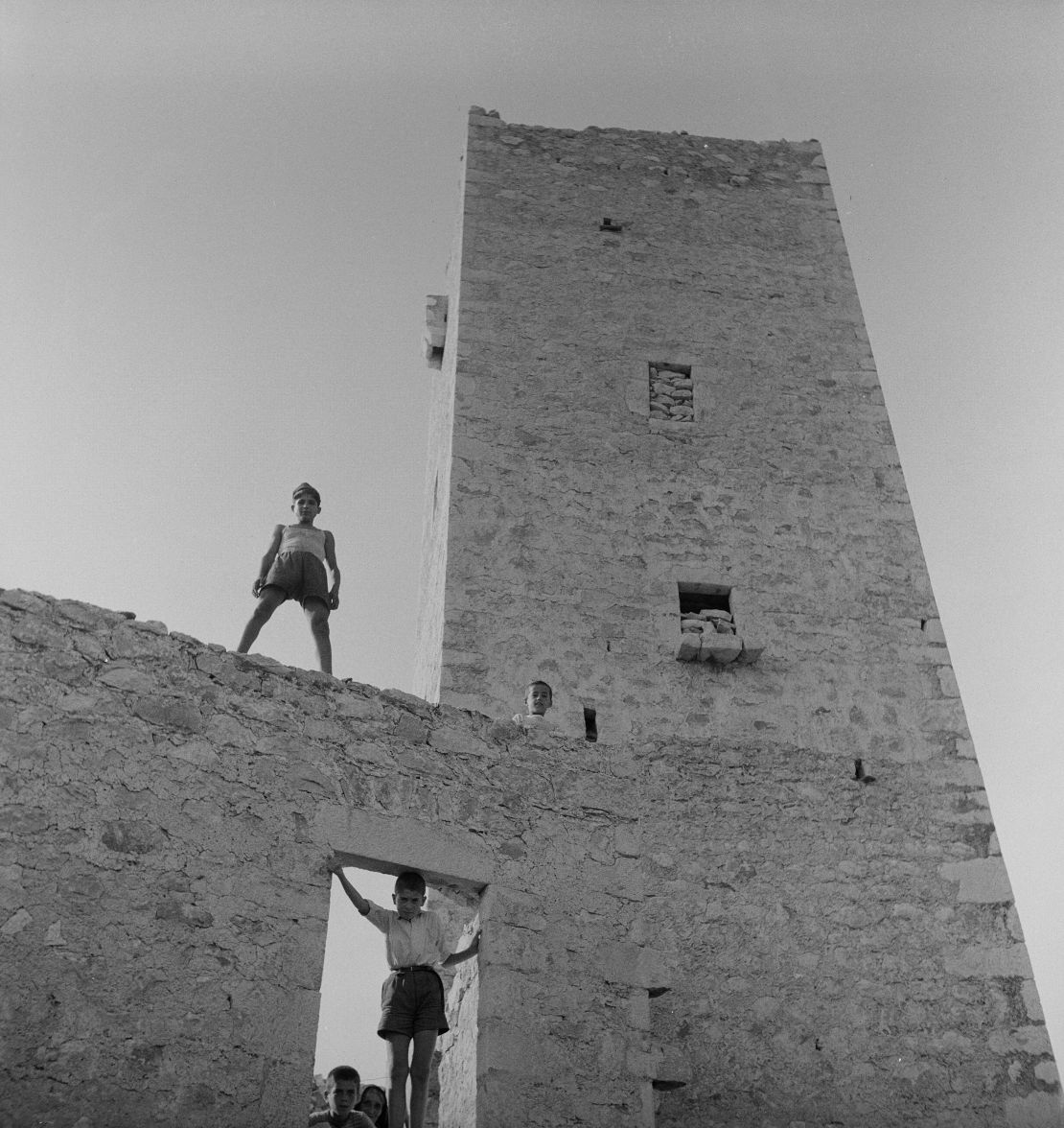 A boy poses on a tower in Greece.