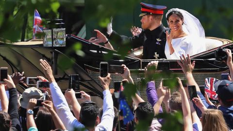 Well-wishers take pictures as Harry and Meghan pass in their carriage.