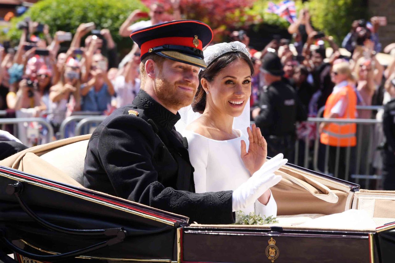 Harry and Meghan ride in an open carriage on their wedding day.
