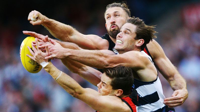 Patrick Ambrose of the Bombers and Cale Hooker of the Bombers, top, compete for the ball against Tom Hawkins of the Cats during the round nine Australian Football League match between the Essendon Bombers and the Geelong Cats at Melbourne Cricket Ground on Saturday, May 19, in Melbourne, Australia.
