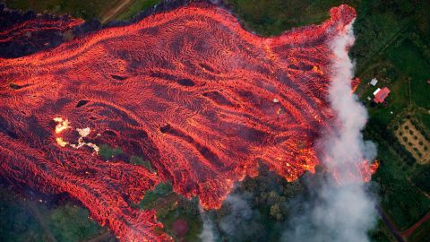 The remains of one home burn on the left as the fast-moving lava approaches another on the right in Pahoa, Hawaii, on Saturday.