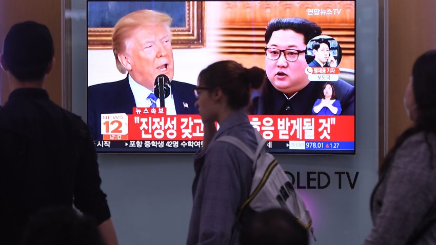People walk past a television news screen showing North Korean leader Kim Jong Un (R) and US President Donald Trump (L) at a railway station in Seoul on May 16, 2018. - North Korea threatened on May 16, to cancel the forthcoming summit between leader Kim Jong Un and President Donald Trump if Washington seeks to push Pyongyang into unilaterally giving up its nuclear arsenal. (Photo by Jung Yeon-je / AFP) (Photo credit should read JUNG YEON-JE/AFP/Getty Images)