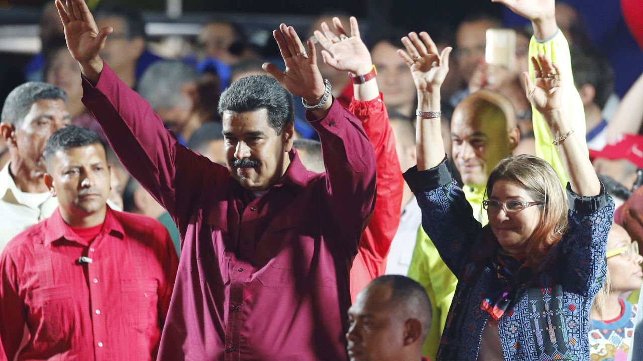 Venezuela's President Nicolas Maduro and his wife, Cilia Flores, wave to supporters at the presidential palace in Caracas. 