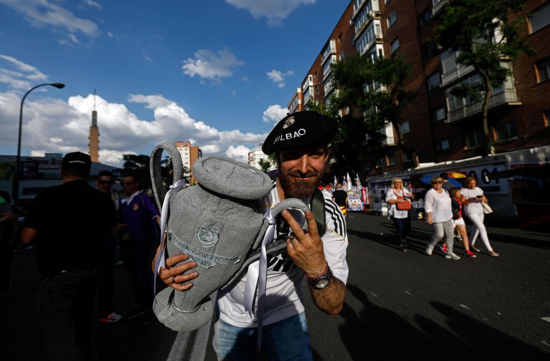 A Real Madrid football team fan holds a replica of the Champions League trophy.