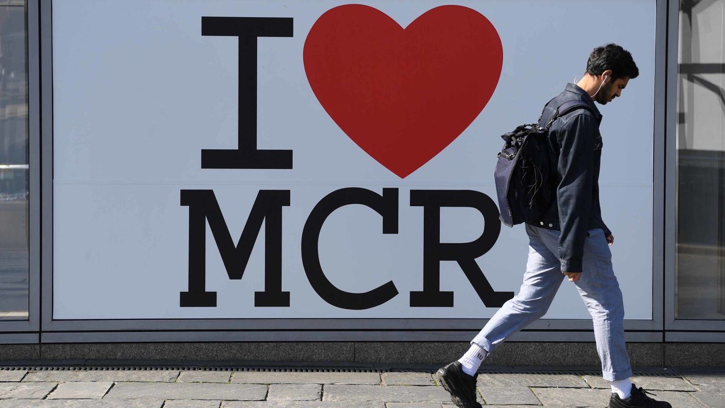 A pedestrian walks past a sign of support set up in the wake of the Manchester Arena bombing in central Manchester on May 22, 2018, the one year anniversary of the deadly attack.