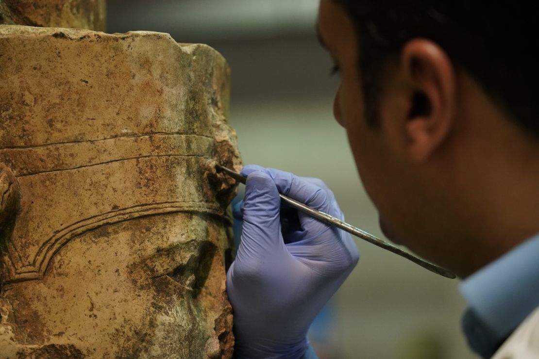 A conservator works on a statue of Amun-Ra in the heavy stone room at the Grand Egyptian Museum conservation center.