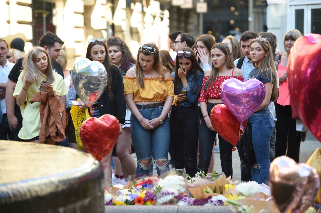 People pay their respects as they look at tributes left in central Manchester on May 22, 2018, the one-year anniversary of the  Manchester Arena attack.