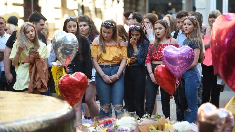People pay their respects as they look at tributes left in central Manchester on May 22, 2018, the one-year anniversary of the  Manchester Arena attack.
