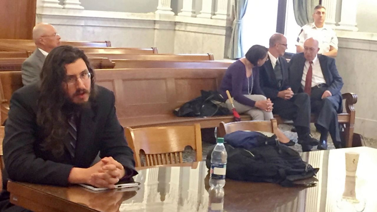 Michael Rotondo (left) at his eviction proceeding in Syracuse, New York. His parents, Mark and Christina, confer with their lawyer in the court gallery behind. 