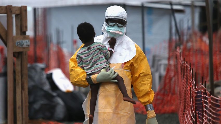 PAYNESVILLE, LIBERIA - OCTOBER 05:  A Doctors Without Borders (MSF), health worker in protective clothing carries a child suspected of having Ebola in the MSF treatment center on October 5, 2014 in Paynesville, Liberia. The girl and her mother, showing symptoms of the deadly disease, were awaiting test results for the virus. The Ebola epidemic has killed more than 3,400 people in West Africa, according to the World Health Organization.  (Photo by John Moore/Getty Images)