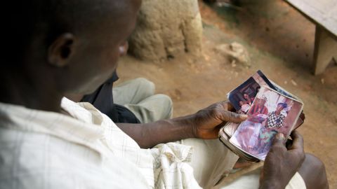Etienne Ouamouno holds a picture of wife Sia Dembadouno and their son, Emile, in front of their family home in the village of Meliandou, Guinea.