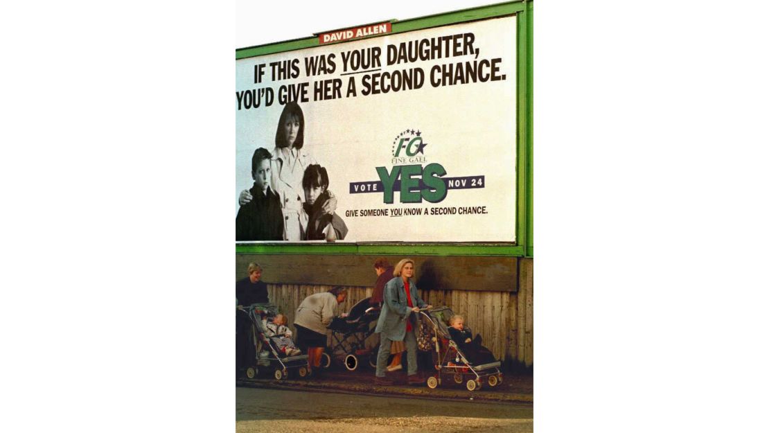 Irish women push strollers under a government-sponsored poster in Dublin, 1995.