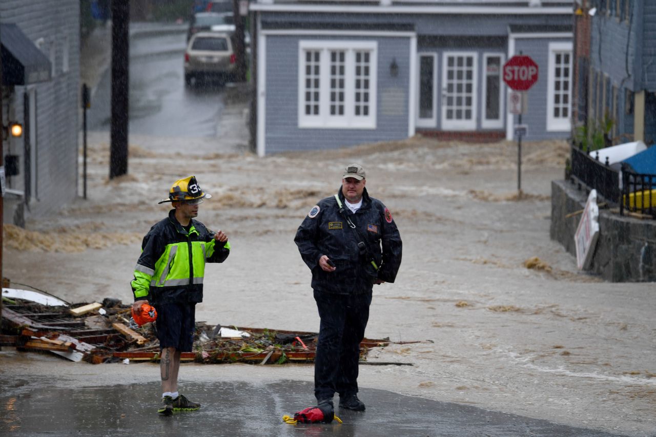 Officials wait for backup as floodwaters race through Main Street on Sunday.