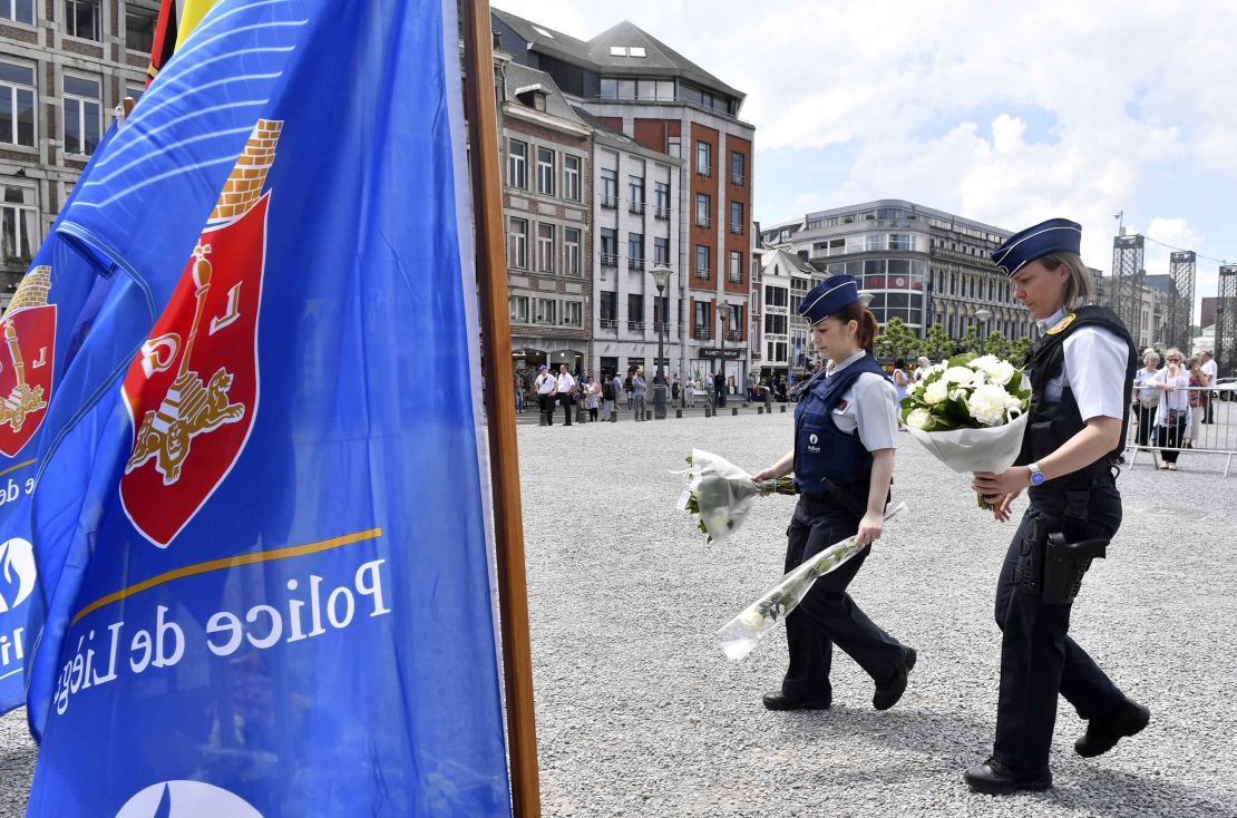 Police prepare to lay flowers on a memorial in Liege, Belgium, a day after a gunman killed three people, including two policewomen. 