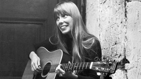 Canadian singer and songwriter Joni Mitchell, strums her guitar outside The Revolution club in London in 1968.